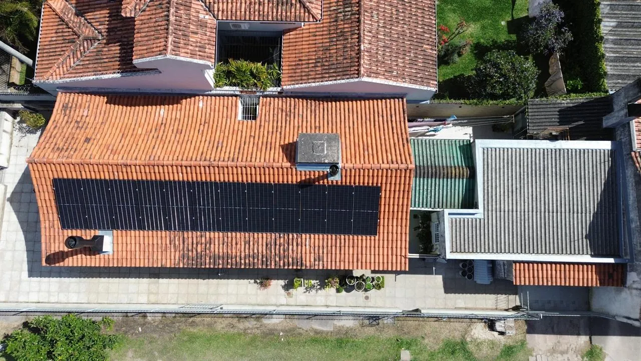 Vista aérea de casa com módulos fotovoltaicos instalados em telhado de telhas cerâmicas