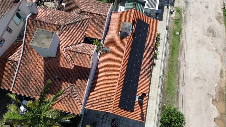 Vista aérea de casas com fileira de módulos fotovoltaicos em telhado cerâmico