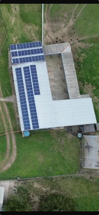 Vista aérea de galpão rural com módulos fotovoltaicos instalados no telhado