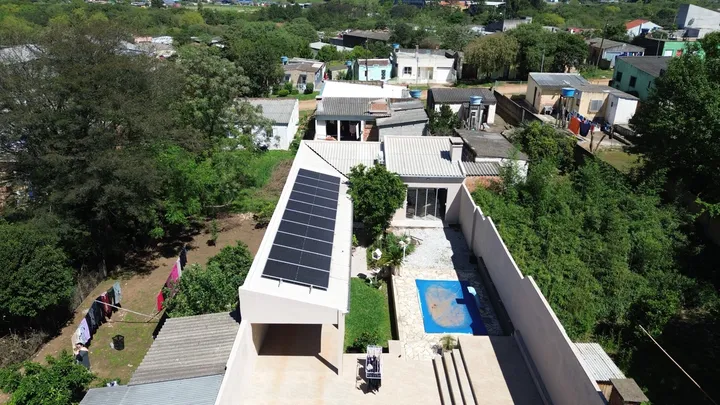 Vista aérea de residência com piscina e módulos fotovoltaicos instalados no telhado